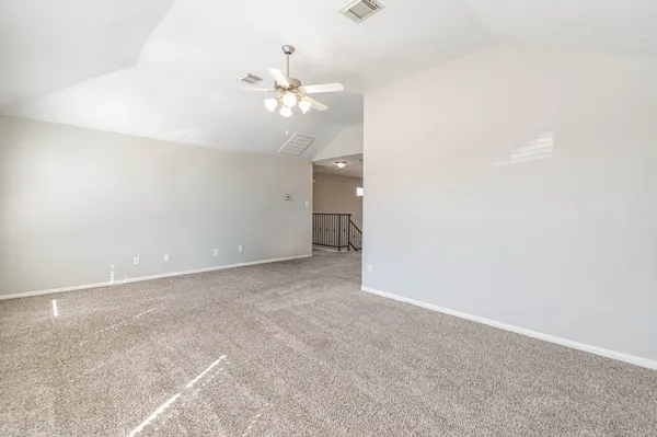 a view of an empty room with a chandelier fan