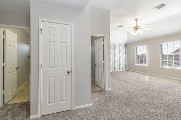 an empty room with windows and ceiling fan