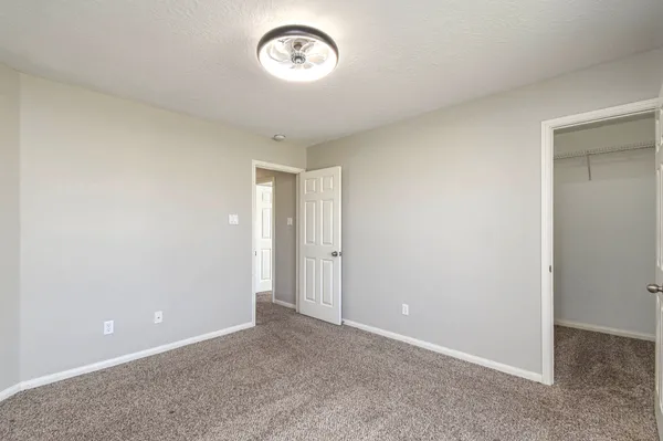 an empty room with a fan & a window