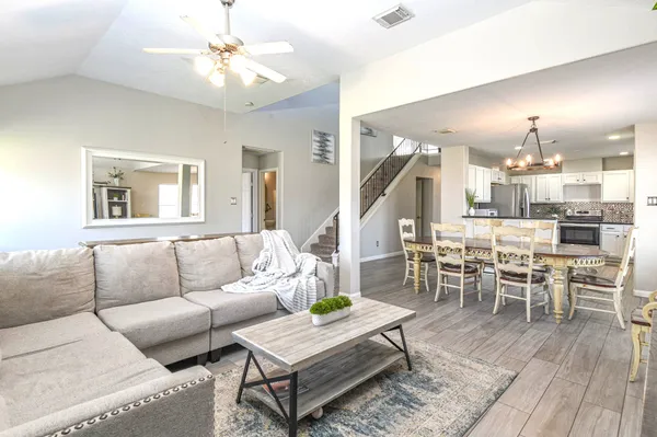 a living room with furniture kitchen view and a wooden floor