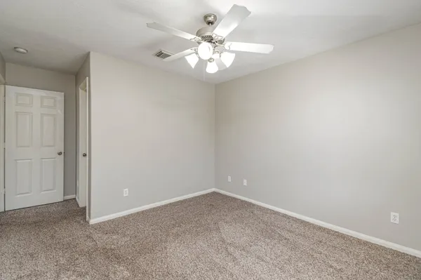 a view of an empty room with a chandelier fan