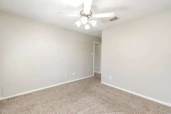 an empty room with a chandelier fan and windows