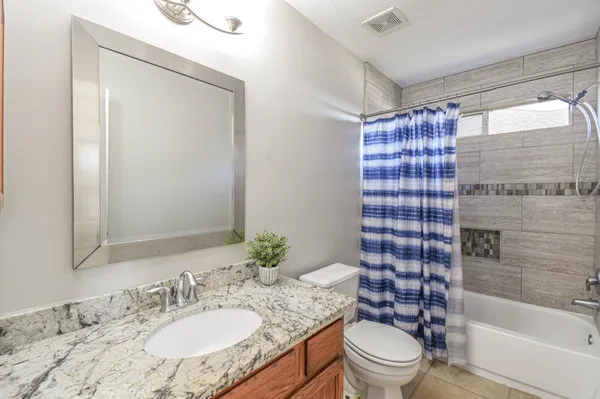 a bathroom with a granite countertop toilet a sink and a bathtub