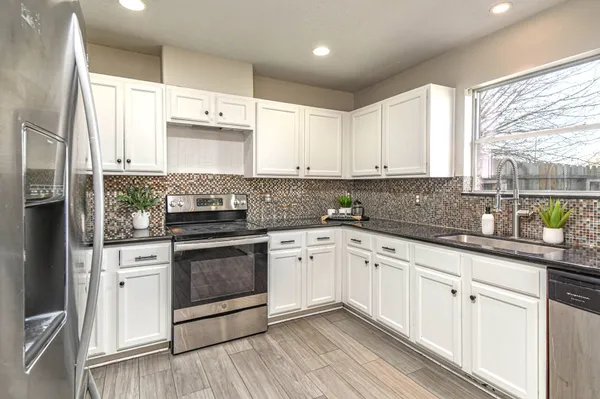 a kitchen with granite countertop a stove a sink and a refrigerator