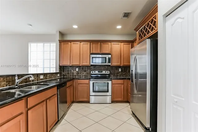 a kitchen with stainless steel appliances granite countertop a stove a sink and a refrigerator