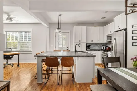 a kitchen with stainless steel appliances granite countertop a table chairs stove microwave and cabinets