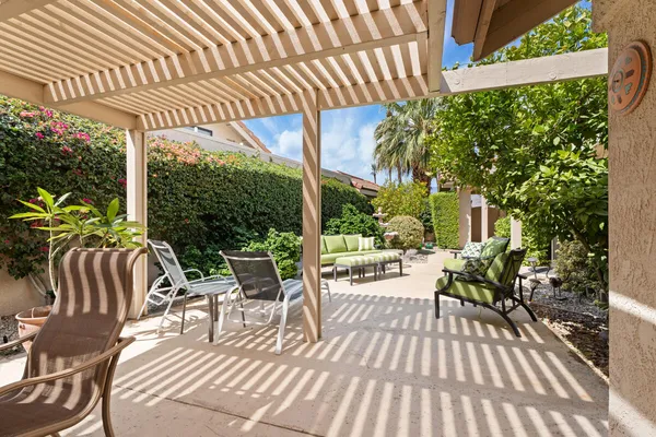 a view of a patio with table and chairs potted plants and floor to ceiling window