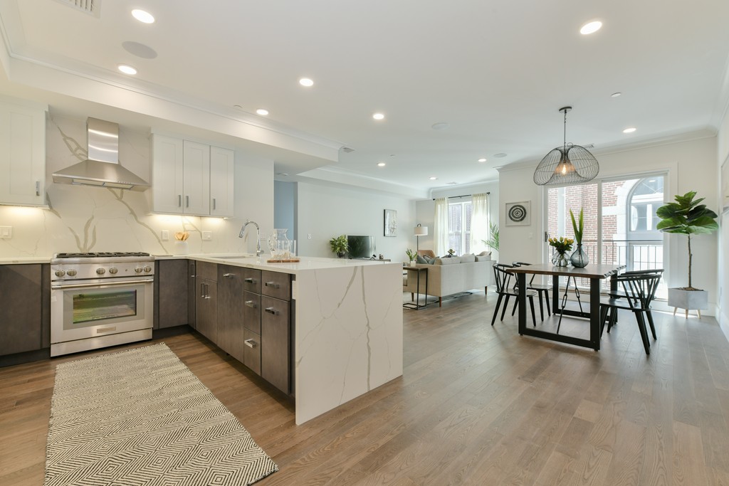 10 Sydney Street, Unit 7 Boston, MA 02125 - Photo 25 of 26 a kitchen with stainless steel appliances kitchen island granite countertop a stove top oven a sink a dining table and chairs with wooden floor