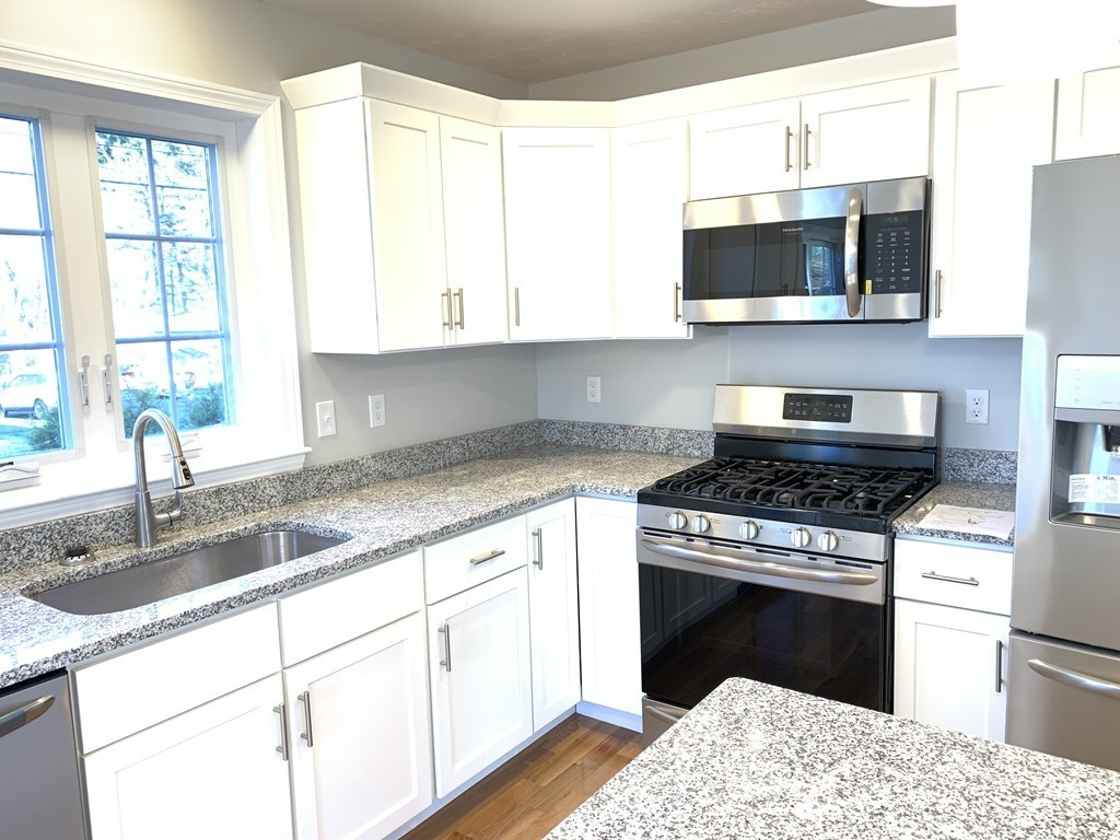 11 Mendon Road, Unit A Attleboro, MA 02703 - Photo 12 of 24 a kitchen with stainless steel appliances granite countertop a sink stove and microwave