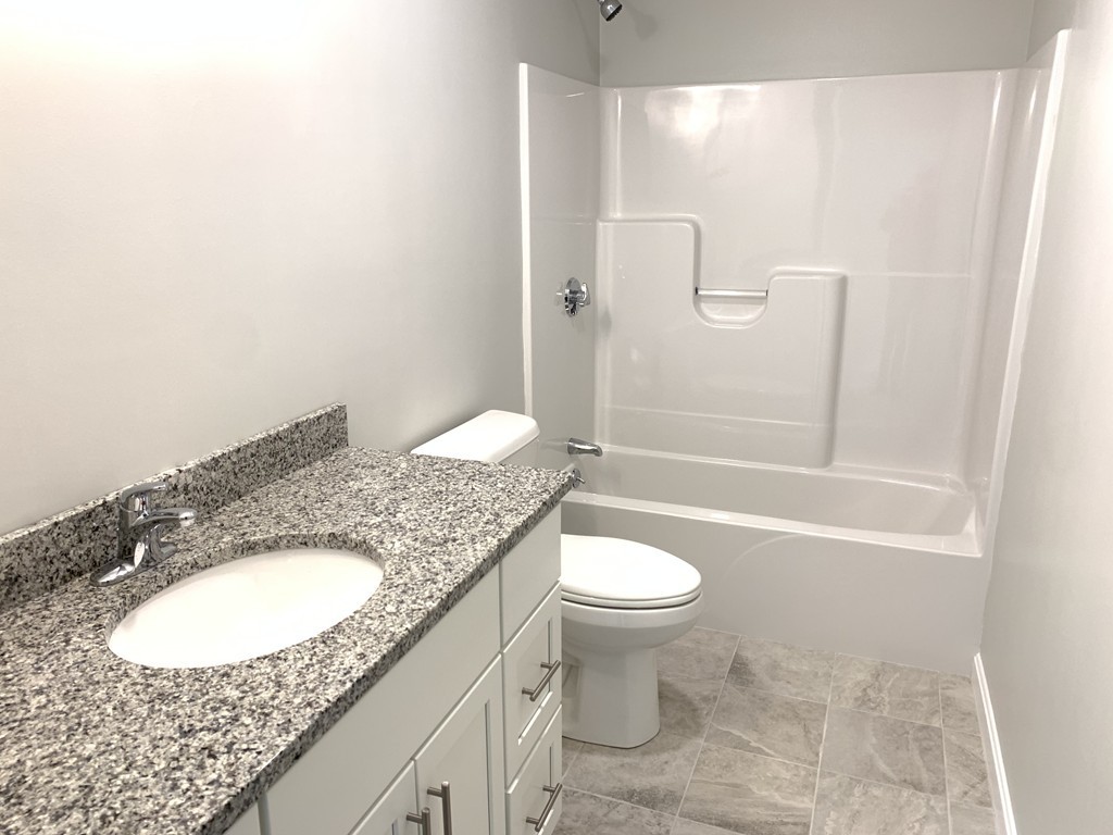 11 Mendon Road, Unit A Attleboro, MA 02703 - Photo 18 of 24 a bathroom with a granite countertop sink a toilet a mirror and bathtub