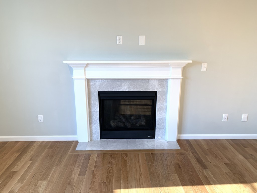 11 Mendon Road, Unit A Attleboro, MA 02703 - Photo 7 of 24 a view of an empty room with wooden floor and a fireplace