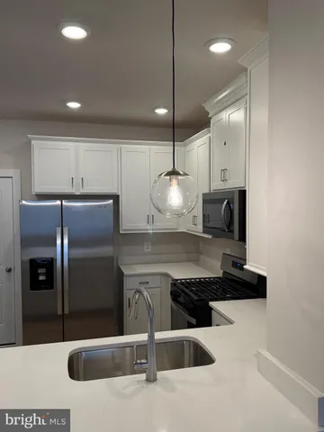 a kitchen with stainless steel appliances kitchen island granite countertop a refrigerator a oven a sink a counter and chairs