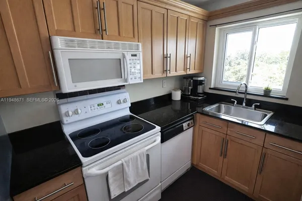 a kitchen with granite countertop white cabinets and white appliances