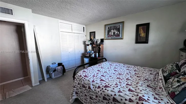 a bedroom with a bed and a refrigerator