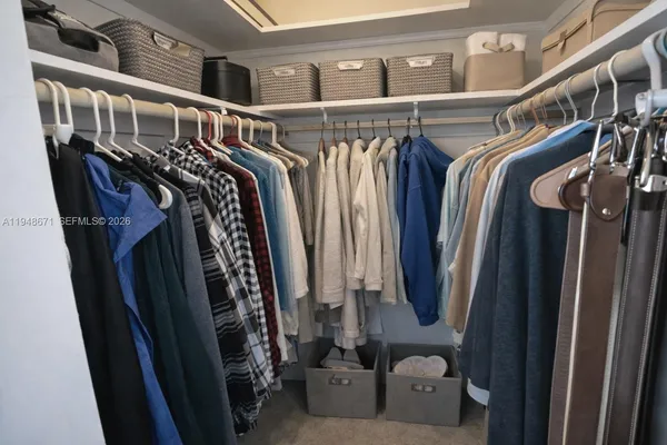 a view of walk in closet with clothes and shoes