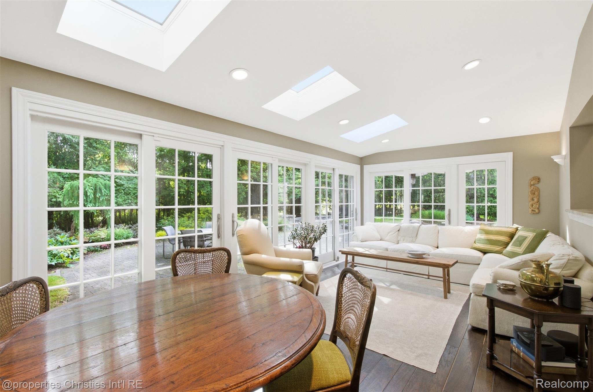 25235 Canterbury Road Franklin, MI 48025 - Photo 19 of 56 Spacious living area featuring multiple skylights and recessed lighting, dark wood-finish flooring, and expansive glass paneled doors opening to the exterior