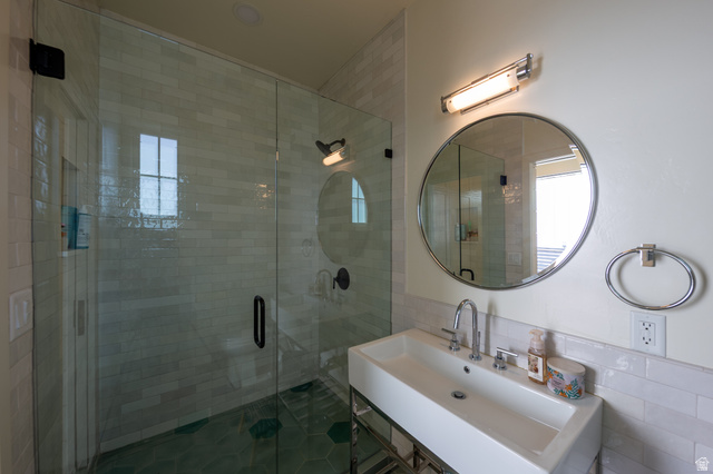 630 East Center Street Alpine, UT 84004 - Photo 86 of 115 Modern bathroom featuring a rectangular vessel sink with polished chrome fixtures, a frameless glass shower enclosure, and a round wall-mounted mirror