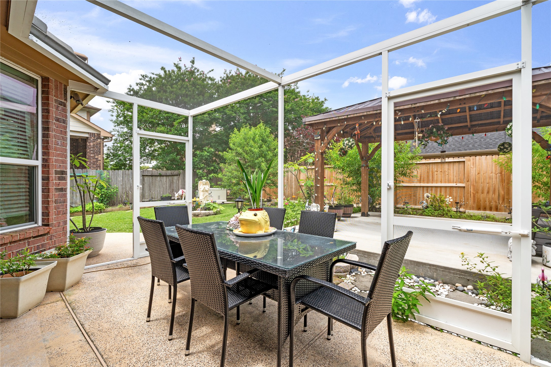 5802 Layton Meadows Lane Spring, TX 77379 - Photo 36 of 42 Inside the screened patio. Wicker dining set with glass table, open views to the backyard and gazebo. Bright and airy.
