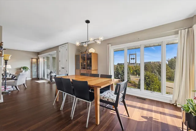 a dining room with wooden floor a chandelier a glass table and chairs