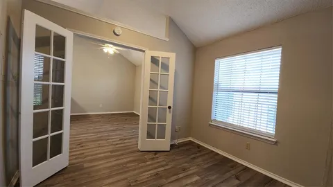 an empty room with wooden floor and windows