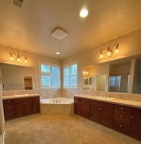 a spacious bathroom with a double vanity sink a large mirror and a bathtub
