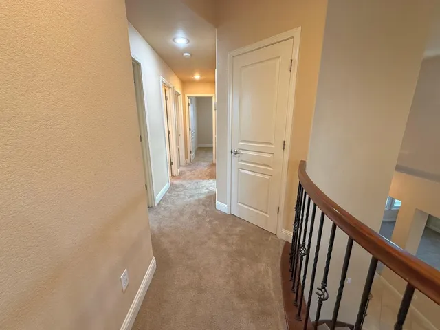 a view of a hallway with wooden floor and staircase