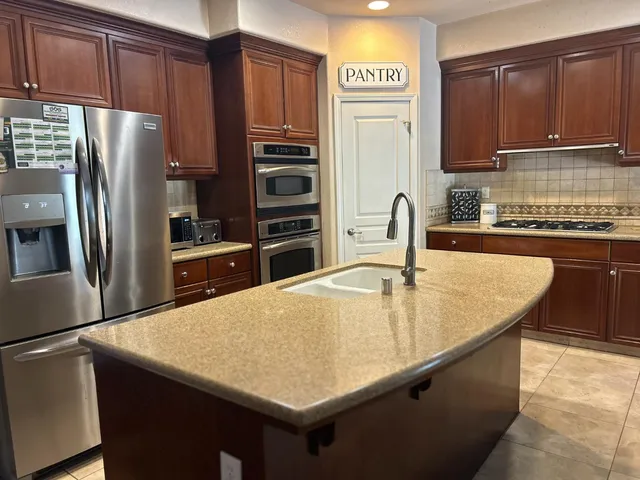 a kitchen with stainless steel appliances a refrigerator a stove a sink cabinets and a counter space