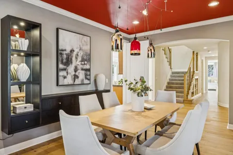 a kitchen with stainless steel appliances kitchen island granite countertop a stove a refrigerator a sink a dining table and chairs with wooden floor