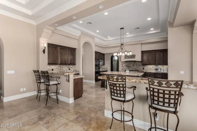 a kitchen with stainless steel appliances kitchen island granite countertop a dining table chairs refrigerator and microwave