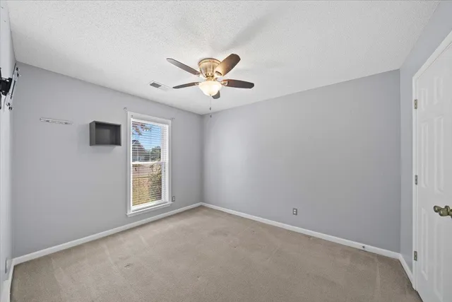 an empty room with windows and fan