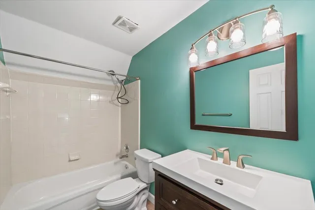 a bathroom with a sink vanity mirror toilet and bathtub
