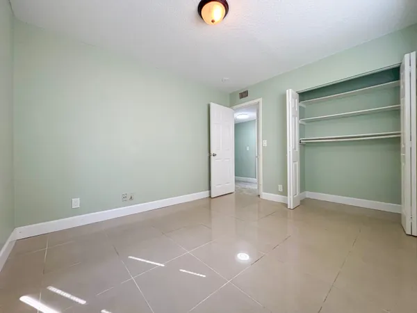 a view of an empty room with closet and a window