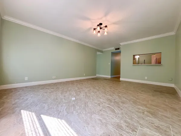 a view of an empty room with a chandelier fan