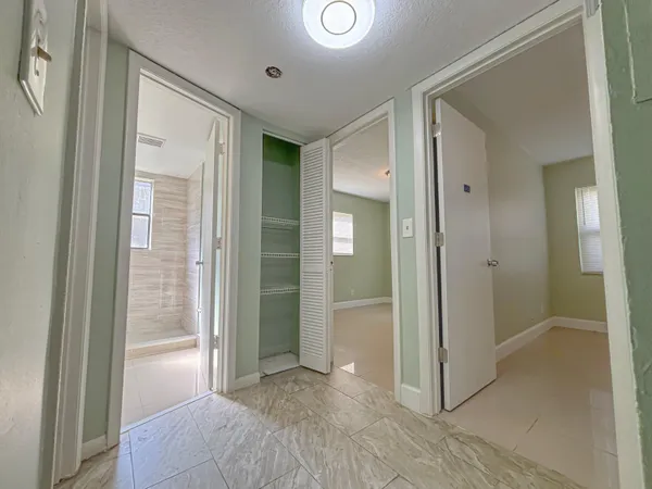 a view of a hallway with wooden floor and a bathroom