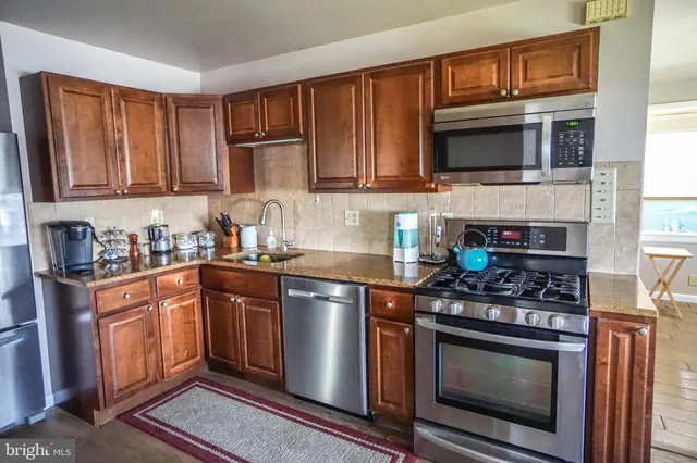 a kitchen with stainless steel appliances granite countertop a stove microwave and sink