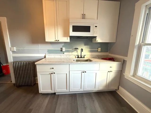 a kitchen with stainless steel appliances granite countertop a sink a microwave cabinets and a wooden floor