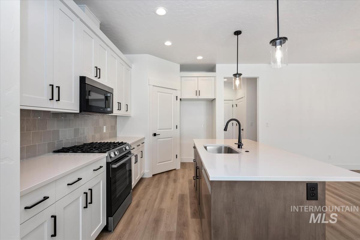 768 South Calhoun Lane Star, ID 83669 - Photo 13 of 36 Modern kitchen featuring white shaker cabinetry, stainless steel appliances, light-toned countertops, a tile backsplash, and wood-finish flooring