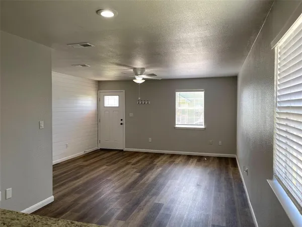 an empty room with wooden floor and windows