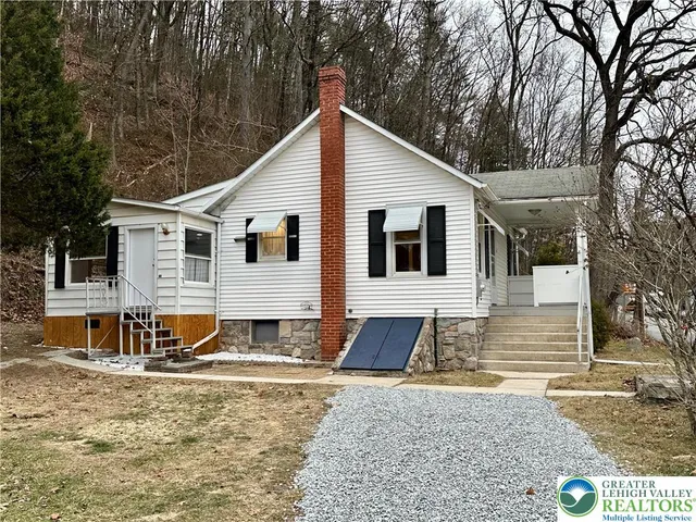a view of a white house with large windows next to a road