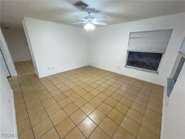 en empty room with a fireplace and a chandelier fan
