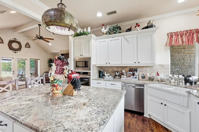 a kitchen with stainless steel appliances granite countertop a refrigerator a stove top oven a sink dishwasher and a dining table with wooden floor