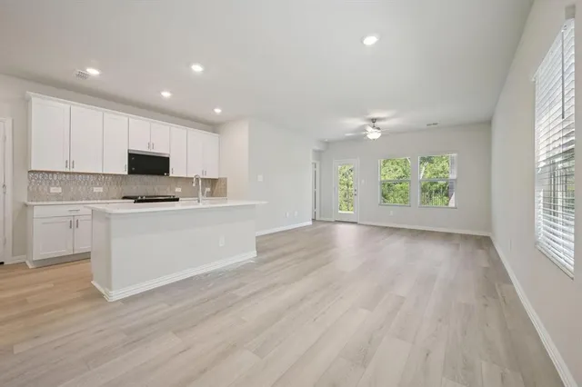 a view of kitchen with granite countertop cabinets and window