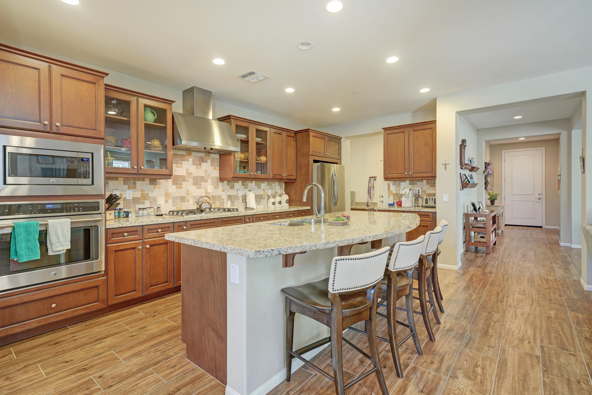 a kitchen with stainless steel appliances granite countertop a kitchen island a stove a sink a dining table and chairs