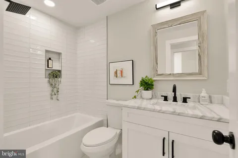 a bathroom with a granite countertop sink a toilet and bathtub