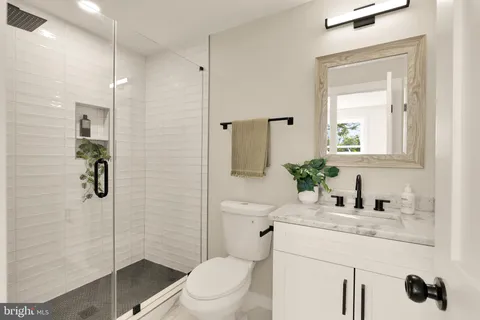 a bathroom with a granite countertop sink a toilet and shower