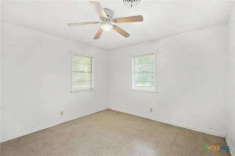 an empty room with a window and a fan