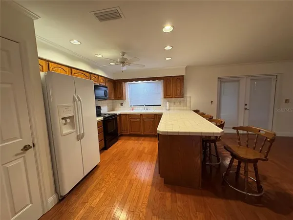 a kitchen with stainless steel appliances granite countertop a refrigerator a sink dishwasher and a stove with wooden floor