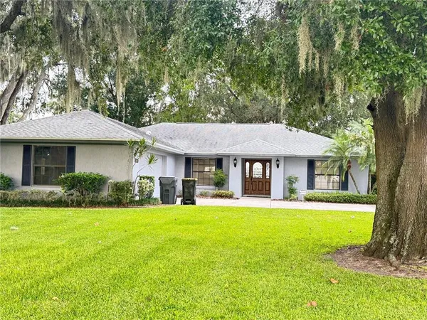 a front view of a house with a yard and trees