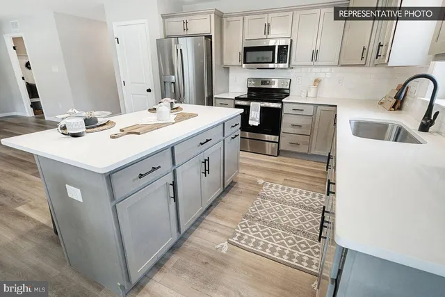 a kitchen with stainless steel appliances kitchen island granite countertop a sink stove and refrigerator