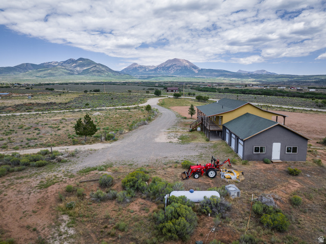 1 Tobe Day Road La Sal, UT 84530 - Photo 32 of 67 Expansive property featuring a multi-tone exterior, a prominent garage structure with multiple bay doors, and a wrap-around elevated deck